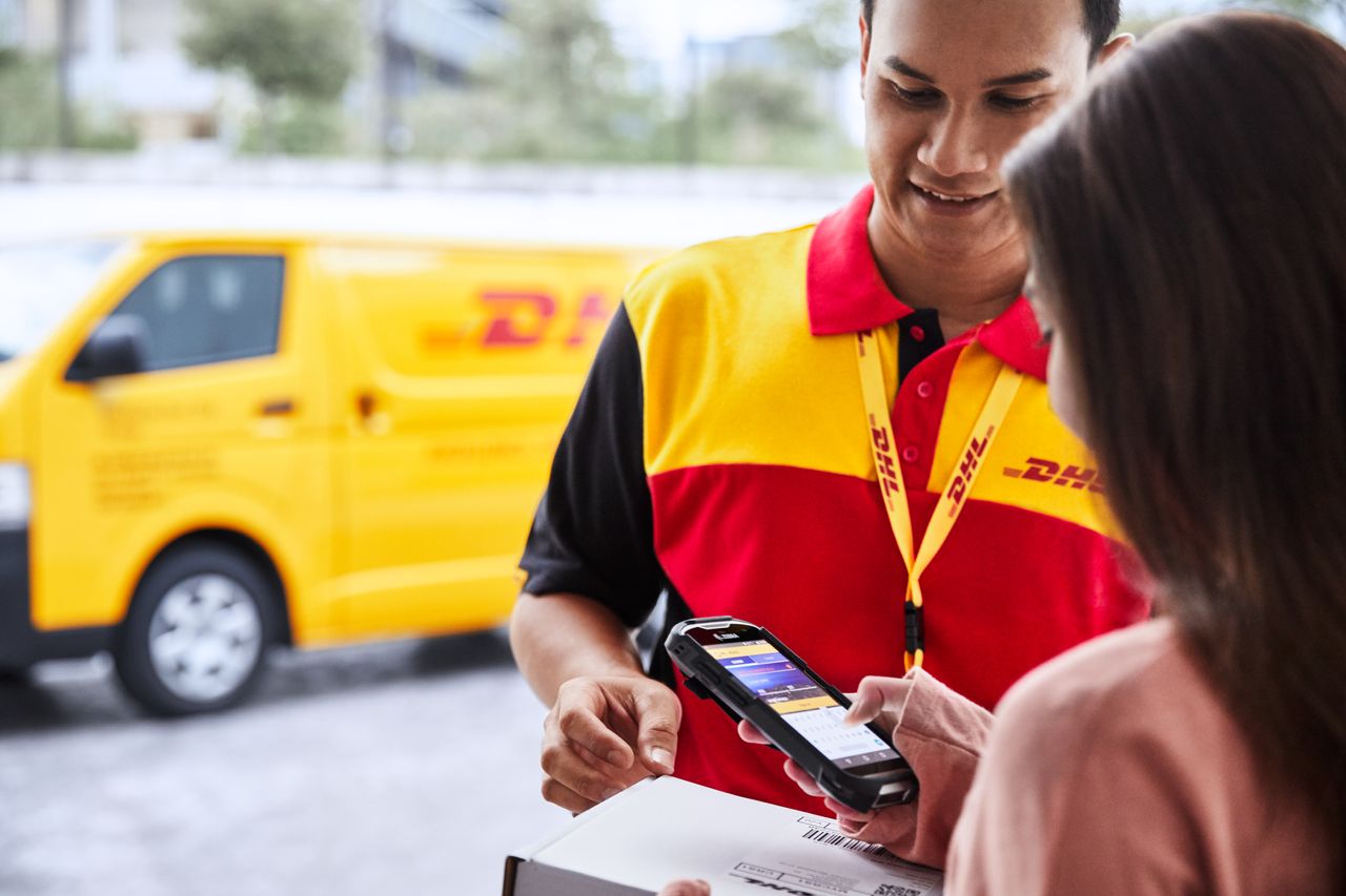 Curier DHL scanând un colet pentru livrare rapidă în Romania prin Post Express.